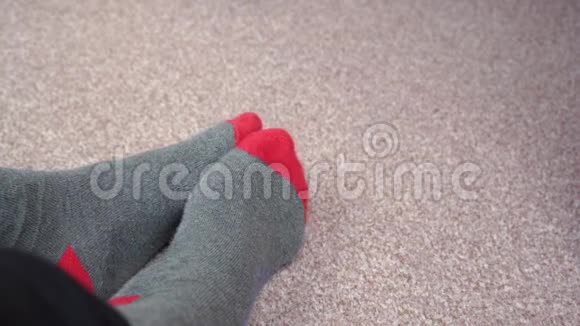 双脚穿着红灰色袜子在浅棕色地毯上相互摩擦视频的预览图