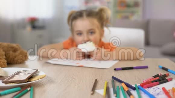 可爱的女孩子吃甜奶油蛋糕坐桌童年快乐视频的预览图