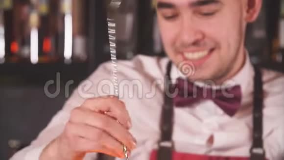 酒吧男将鸡尾酒配料与长勺在高杯中混合视频的预览图
