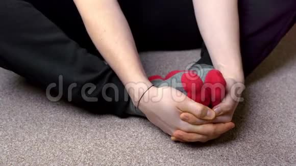 双手放在浅棕色地毯上的红灰色袜子里视频的预览图