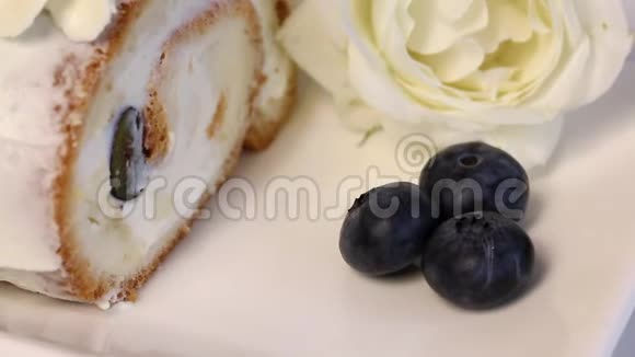 海绵蛋糕涂上奶油用干蓝莓和新鲜薄荷叶装饰附近有一朵白玫瑰特写镜头视频的预览图
