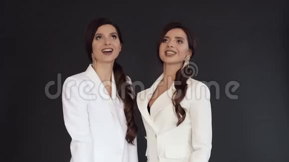 漂亮的双胞胎姐妹穿着优雅的白色西装玩五彩纸屑视频的预览图