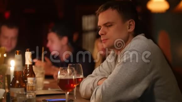 迷人的愤怒和疲惫的男人坐在酒吧里柔和的室内照明和喝淡啤酒视频的预览图