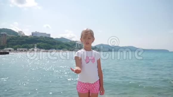 一个女孩在海边向水中扔硬币女孩拿着硬币扔进海里视频的预览图