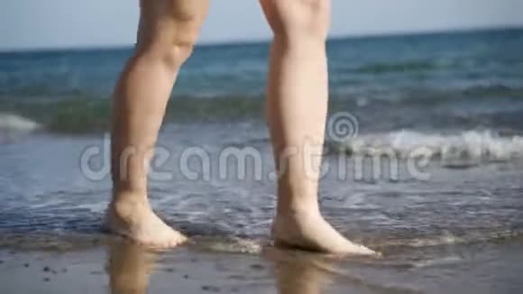 女孩沿着水边走女人在沙滩上沿着海岸走视频的预览图