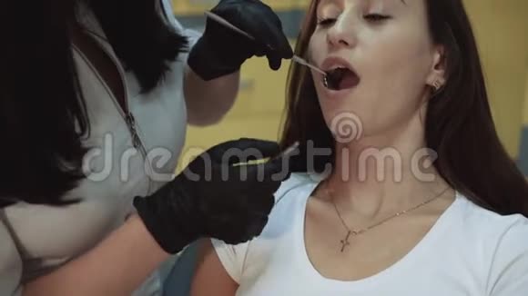年轻漂亮的女孩坐在牙科柜里接受治疗和咨询视频的预览图