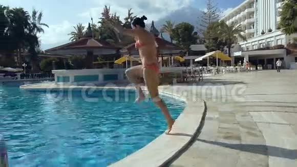 美丽的年轻女子跳进酒店的游泳池溅起水花视频的预览图