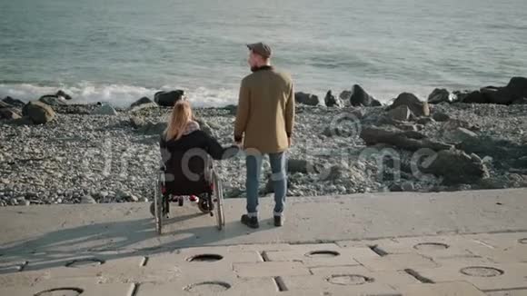 轮椅使用者和健康的男人手牵手观看海景视频的预览图