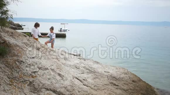 男孩和女孩走在岩石海岸初恋浪漫的散步暑假视频的预览图