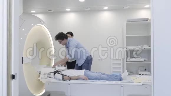 与核磁共振扫描仪合作做病人头部断层扫描的实习生视频的预览图