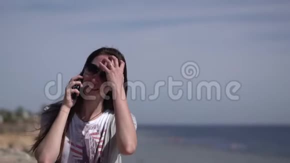 一个微笑的女孩在海滩上打电话视频的预览图