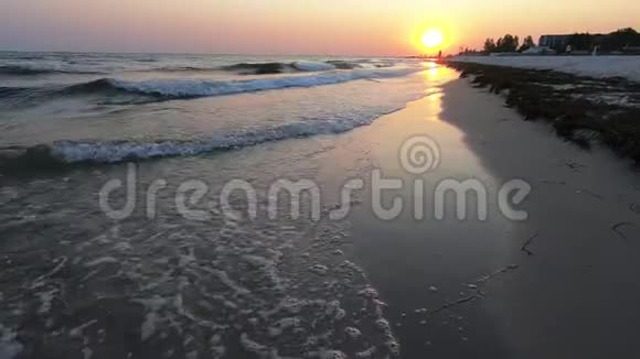海滩日落有橙色的太阳和泡沫的波浪视频的预览图