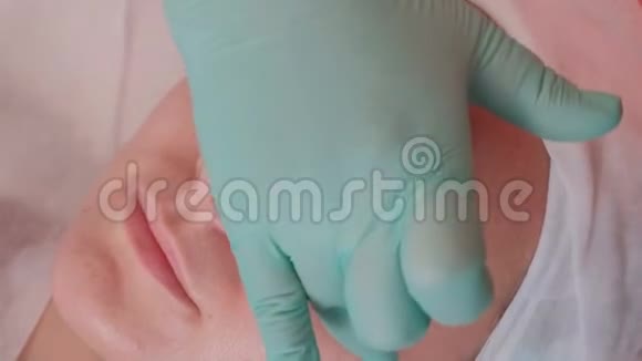 美容院漂亮女孩的脸蓝手套美容师用透明的防皱凝胶视频的预览图