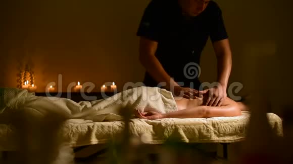 特写水疗按摩妇女肩膀和背部男人的手在黑暗的房间里给女人按摩里面有蜡烛视频的预览图