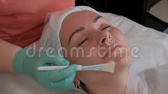 美容师在年轻女性的脸上涂上滋养凝胶或奶油美容界的美女视频的预览图