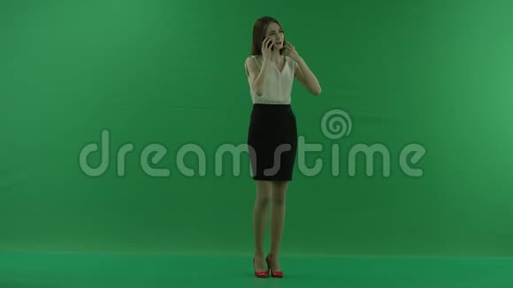 穿着白衬衫和黑裙子的年轻美女站在前面用手机聊天视频的预览图