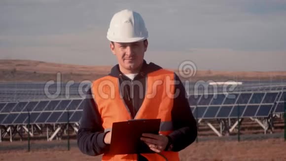 工程师站在田野里背景是太阳能电池板看着摄像机记下了视频的预览图