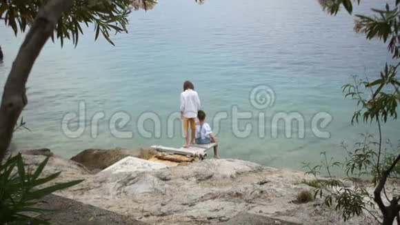 青少年男孩和女孩坐在海滨暑假异国他乡的假日视频的预览图