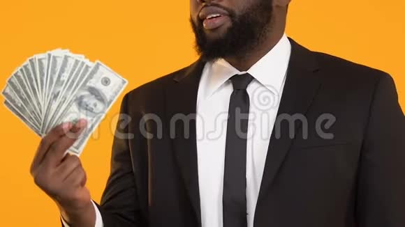 穿着西装的快乐非裔美国男人展示了一大堆美元和大拇指视频的预览图