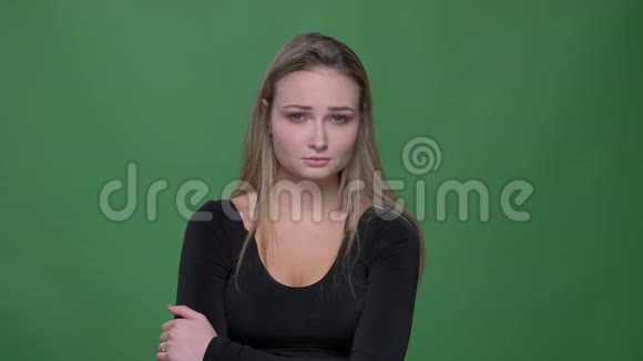 忧郁的年轻模特穿着黑色衬衫在绿色背景下悲伤地看着镜头的肖像视频的预览图