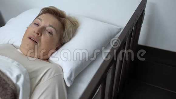 生病的退休妇女躺在病床上用颤抖的手闭着脸视频的预览图