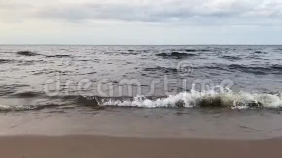 湖岸阴沉的阴天海浪在沙滩上翻滚视频的预览图