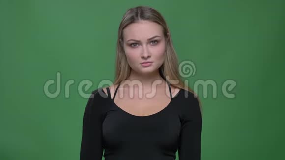 一幅年轻女商人穿着黑色衬衫在绿色背景下怀疑地看着镜头的肖像视频的预览图