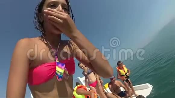 快乐的少女从船上跳到大海在户外看相机视频的预览图