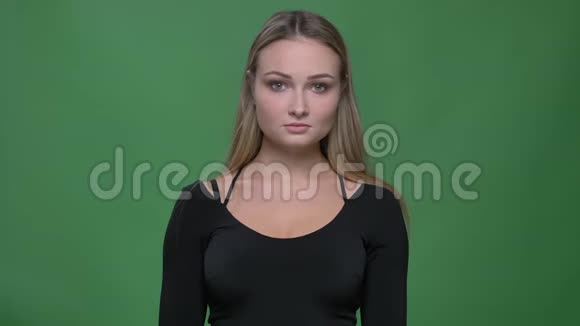 穿着黑色上衣的年轻女商人在绿色背景下严肃地观看镜头的肖像视频的预览图
