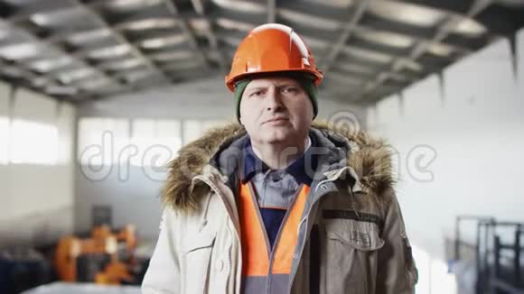 戴着安全帽穿着工作服的人正站在机库的中间看着他的手表视频的预览图
