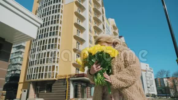 一个快乐的女孩走在街上手里拿着一束黄色的郁金香视频的预览图