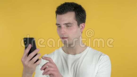 年轻人在黄色背景下使用智能手机为成功而兴奋视频的预览图