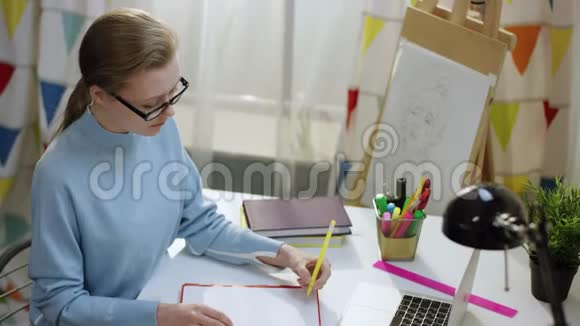 年轻女子在笔记本上画画把纸条贴在那里视频的预览图