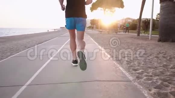 傍晚时分运动员在海边的城市公园慢跑视频的预览图