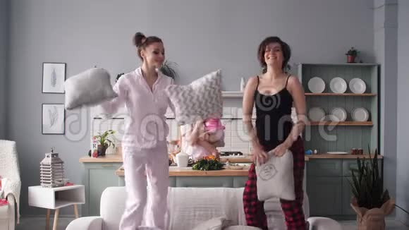 有趣快乐的女人在家里跳舞打枕头仗视频的预览图