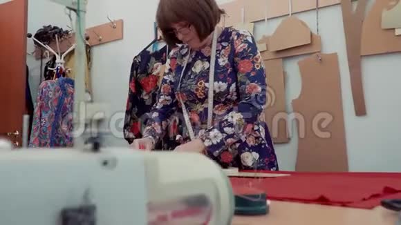 戴着白种人眼镜的成年女性在缝纫机上测量并用假人做标记视频的预览图