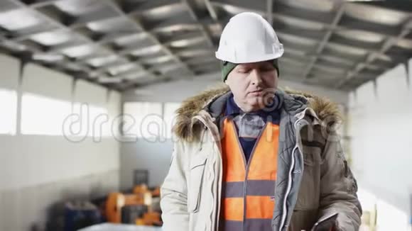 一个戴着安全帽穿着工作服的人正站在机库的中央对着镜头用手机说话视频的预览图