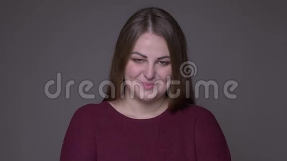年轻的超重白种人女性的特写镜头带着羞怯的微笑看着镜头背景被隔离视频的预览图