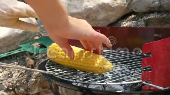 年轻女子用漂亮的指甲在烤架上收集玉米穗视频的预览图