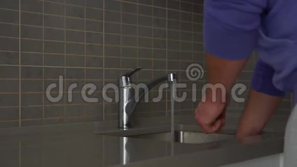 丈夫用海绵在厨房水槽里洗杯子和盘子视频的预览图