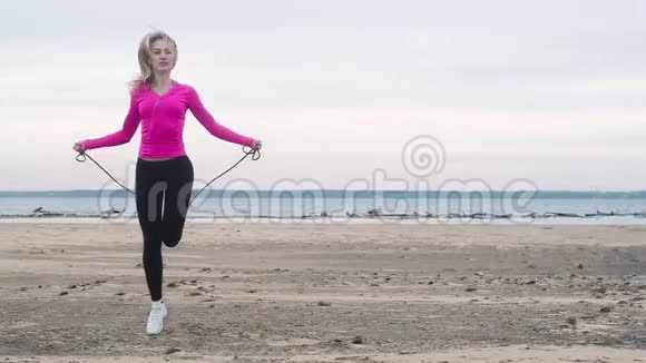 运动女孩在沙滩上跳绳阴天健身视频的预览图