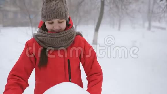 穿着红色kopcke的少女在街上雕刻一个雪人视频的预览图