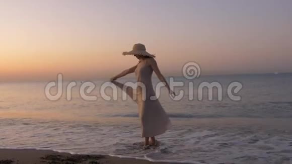 快乐健康浪漫的女人穿着连衣裙和草帽在海滩上兜圈子视频的预览图