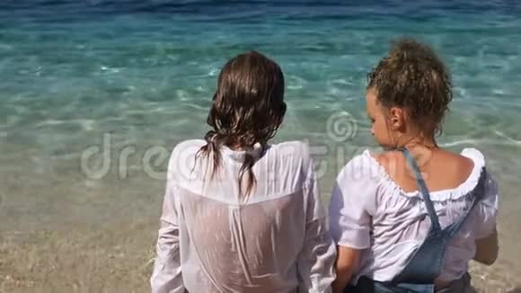 快乐的孩子们一对朋友穿着湿衣服的兄弟姐妹坐在亚得里亚海的海岸上视频的预览图