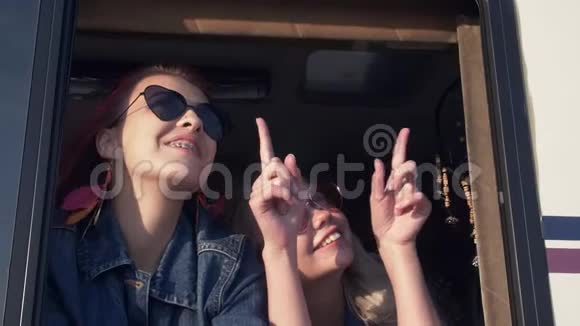 日落时分一对戴着太阳镜的年轻女子正在拖车的窗口微笑视频的预览图
