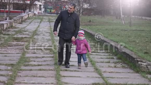 孙女和爷爷牵着手走在城市公园里慢动作视频的预览图