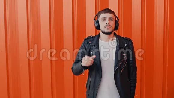 时尚男士戴耳机听东西耳机音乐接近橙色背景视频的预览图