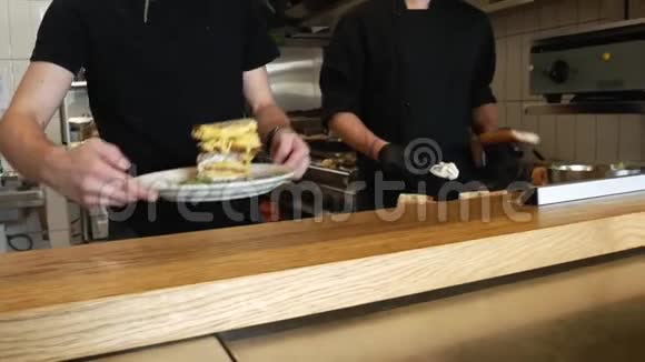 厨师在桌子上放一个切片奶酪三明治在盘子上三明治里有特色菜和生菜炉台视频的预览图