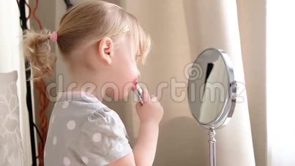 镜子前一个漂亮的小女孩学会化妆小女孩把嘴唇涂了视频的预览图
