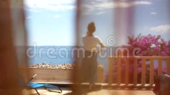 可爱的年轻女子在阳光明媚的露台上从窗帘后面的后视镜海滨度假胜地女子日视频的预览图